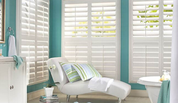 white plantation window shutters in teal bathroom