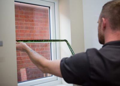 Professional blind fitter measuring a window for blinds